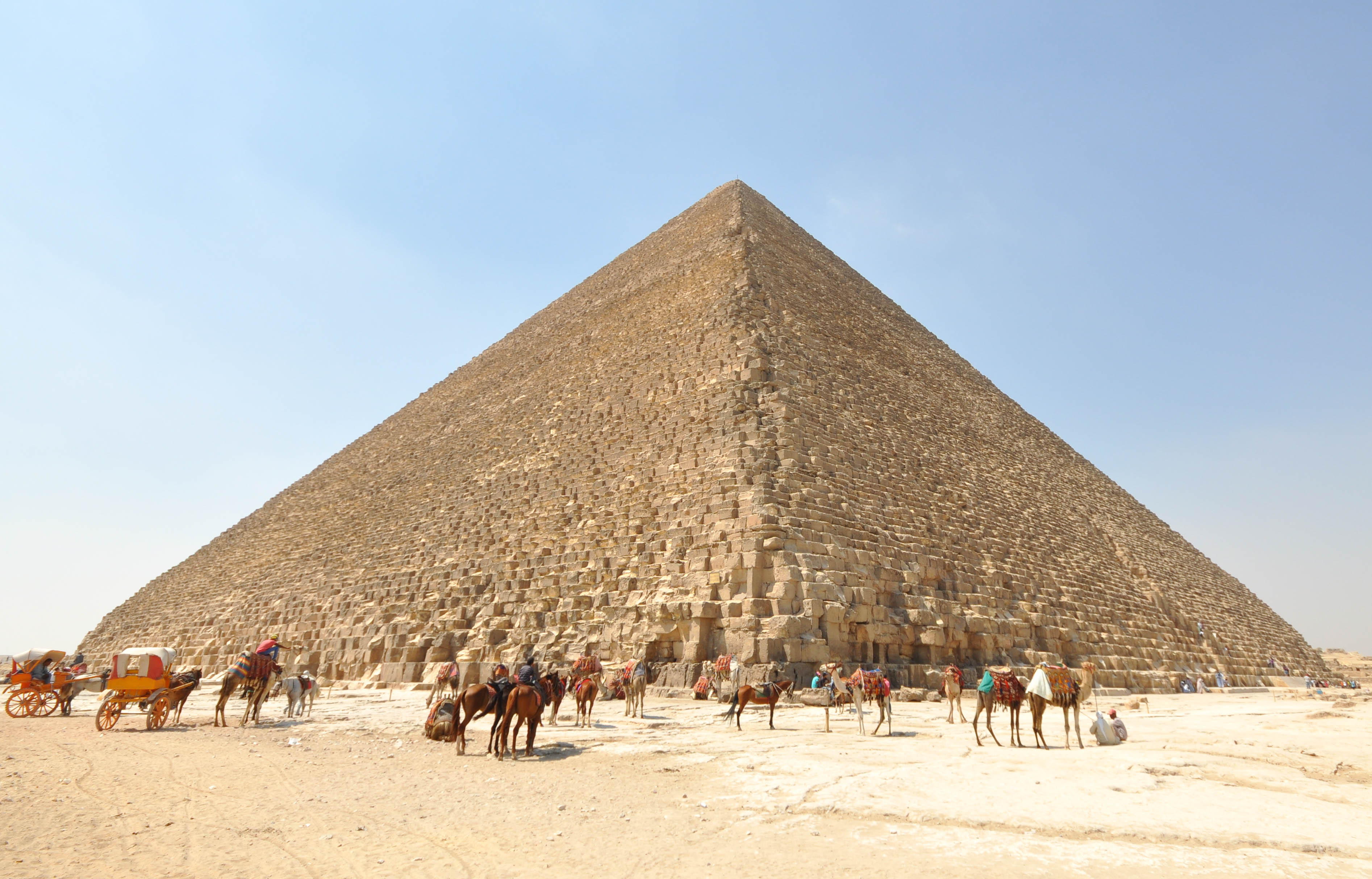 The Great Pyramid of Khufu rising above people and camels at its base.